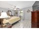 Well-lit bedroom features tile floors, a bed, ceiling fan, and dark wood furnishings and decor at 923 Oleander St, The Villages, FL 32159