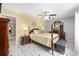 Bedroom with yellow accent wall, 4-poster bed, tile floors, ceiling fan, and dark wood furnishings at 923 Oleander St, The Villages, FL 32159