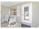 Close-up of the welcoming front porch with a decorative door and comfortable rocking chairs, creating a cozy entrance at 923 Oleander St, The Villages, FL 32159