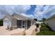 Exterior rear view with a screened lanai area, a patio, and well-maintained landscaping at 971 Margaux Trl, The Villages, FL 32162
