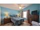 Comfortable bedroom with a ceiling fan, wood floors, and blue walls at 971 Margaux Trl, The Villages, FL 32162