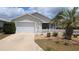 Charming home featuring a well-maintained lawn, a white picket fence, and a two-car garage at 971 Margaux Trl, The Villages, FL 32162