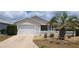 Charming home featuring a well-maintained lawn, a white picket fence, and a two-car garage at 971 Margaux Trl, The Villages, FL 32162