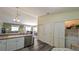 Functional kitchen featuring white cabinets, laminate flooring, and a view into the living and dining areas at 971 Margaux Trl, The Villages, FL 32162