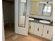 Bathroom with a dual vanity, mirrored cabinets and adjacent walk-in closet with storage at 1030 Vermont Ave, Lady Lake, FL 32159