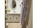 Bathroom with tiled vanity, oval mirror, and a shower with patterned curtain at 1030 Vermont Ave, Lady Lake, FL 32159