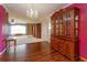 A formal dining area features hard wood floors and a dark-stained hutch and magenta accent wall at 1110 Fairfax St, Leesburg, FL 34748