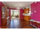 Formal dining room area with view of sun room, magenta accent wall, and hardwood floor at 1110 Fairfax St, Leesburg, FL 34748
