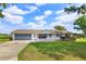 Charming single-story home with a lush green lawn, blue shutters and a matching blue garage door at 1110 Fairfax St, Leesburg, FL 34748