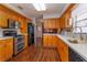 Galley-style kitchen with light-toned counters and wooden cabinets, complete with stainless steel appliances at 1110 Fairfax St, Leesburg, FL 34748