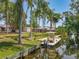 Waterfront backyard features a private dock, boat and lush tropical landscaping with tall palm trees and green grass at 11114 Lake Eustis Dr, Leesburg, FL 34788