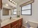 Bathroom featuring wood vanity, large mirror, and towel rack beneath a partially frosted window at 11114 Lake Eustis Dr, Leesburg, FL 34788
