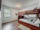 Cozy bedroom with wood-look floors, a window with blinds, and a built-in bunk bed at 11114 Lake Eustis Dr, Leesburg, FL 34788