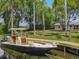 A boat sits moored to a wooden dock in a backyard waterway surrounded by lush landscaping at 11114 Lake Eustis Dr, Leesburg, FL 34788