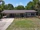 Charming single-story home with a well-manicured lawn, colorful flower beds, carport, and mature trees offering ample shade at 11114 Lake Eustis Dr, Leesburg, FL 34788