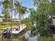 Scenic waterfront view featuring a boat docked along a serene canal surrounded by palm trees and lush greenery at 11114 Lake Eustis Dr, Leesburg, FL 34788