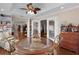 Bright dining room boasts wood floors, a glass topped table, ample seating, and an open view into other rooms at 1121 Ricardo Ave, The Villages, FL 32159
