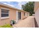 Back patio with sliding glass doors, hose and reel, a spigot, and neutral stucco under a blue sky at 1121 Ricardo Ave, The Villages, FL 32159