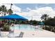 Large community pool surrounded by blue umbrellas, lounge chairs, and palm trees, perfect for recreation and relaxation at 1288 Grady Ln, Davenport, FL 33896