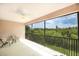 A covered balcony with a metal railing offers a beautiful view of lush green trees and sky at 1288 Grady Ln, Davenport, FL 33896