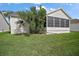 Well-maintained home exterior showcasing a screened-in porch and lush, green lawn at 1318 Guerra Ave, The Villages, FL 32159