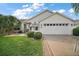 Charming single-story home with a well-manicured lawn, palm trees, and a two-car garage at 1318 Guerra Ave, The Villages, FL 32159