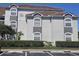 Exterior view of condo building with gray accents, a red tile roof, and well-maintained landscaping in a parking lot at 14049 Fairway Island Dr # 118, Orlando, FL 32837