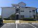 A three-story condo building features gray exterior paint, white stairs, and lush green landscaping with a parking lot at 14049 Fairway Island Dr # 118, Orlando, FL 32837