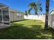 Spacious backyard with a white fence, grass and palm trees, providing privacy and shade at 1451 Rosedale Way, The Villages, FL 32162