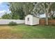 This is a backyard with a shed, a grassy area, and a white fence at 14624 Pine Lake St, Clermont, FL 34711