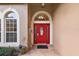 Inviting front entrance with a bright red door, decorative sidelights, and neutral tile flooring at 14624 Pine Lake St, Clermont, FL 34711