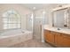 The main bathroom features a soaking tub, a walk-in shower, and wood cabinets at 14624 Pine Lake St, Clermont, FL 34711