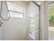 This is a shower with white tiling, a glass sliding door, a window, and a showerhead at 14624 Pine Lake St, Clermont, FL 34711