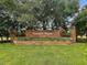 Entrance to Greater Pines community featuring a brick sign surrounded by lush landscaping and mature trees at 14624 Pine Lake St, Clermont, FL 34711