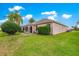 Spacious backyard with lush green grass, a patio area with seating, and mature trees for shade at 1723 Townsend Ter, The Villages, FL 32162