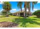 Lush backyard featuring a covered patio, mature trees, manicured lawn and tropical landscaping at 1723 Townsend Ter, The Villages, FL 32162