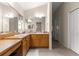 Bathroom with dual sinks, wood cabinets, carpet, and a large mirror offering ample counter space at 1723 Townsend Ter, The Villages, FL 32162