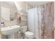 Cozy bathroom with a pedestal sink, toilet, decorative shelves and shower with floral curtain at 1723 Townsend Ter, The Villages, FL 32162