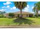 Charming rear exterior featuring a lush green lawn, mature palm trees, and a cozy patio area at 1723 Townsend Ter, The Villages, FL 32162
