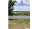 Scenic backyard view featuring a white fence, a tranquil lake, and lush greenery at 1730 Ridgemoor Dr, Mascotte, FL 34753