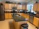 Spacious kitchen features a center island, stainless steel appliances, and wood cabinets for ample storage at 1730 Ridgemoor Dr, Mascotte, FL 34753