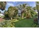 Lush backyard featuring tropical landscaping, green grass, and mature trees in a peaceful setting at 2124 Hames Ln, The Villages, FL 32162