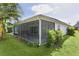 Home exterior with a screened-in porch, lush lawn, and tropical plants at 2124 Hames Ln, The Villages, FL 32162