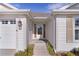 This home welcomes you with its covered front door, adorned with a green welcome mat and beautiful flowering bushes at 2124 Hames Ln, The Villages, FL 32162