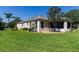 Manicured backyard featuring green lawn, privacy bushes, and a home with screened-in porch at 2237 Avon Loop, The Villages, FL 32162