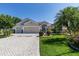 Charming home boasts manicured lawn, mature trees, and a paver driveway at 2237 Avon Loop, The Villages, FL 32162