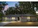 Charming single-story home with a well-maintained lawn, mature trees, and a welcoming driveway at dusk at 227 Oak Rd, Winter Springs, FL 32708