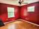 Bedroom featuring laminate flooring, two windows, red walls, and a ceiling fan at 26 Weston Rd, Leesburg, FL 34748
