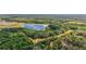 Wide aerial view showcases a lake surrounded by lush trees, highlighting the serene and private location at 27011 Se Highway 42, Umatilla, FL 32784