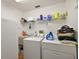 Functional laundry room with washer, dryer, utility sink, and ample shelving at 27011 Se Highway 42, Umatilla, FL 32784